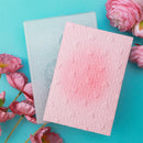 Two textured greeting cards on a turquoise background with pink flowers.