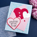 Card with heart design and 'sending virtual hugs' text, surrounded by pink flowers on a dark blue background.