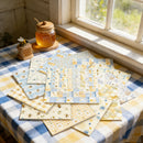 Set of quilt blocks on a table with a jar of honey and a bee decoration near a window.