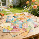 Colorful watercolor paper sheets on a wooden table with flowers in the background