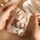 Beige drawstring bag with lace and floral design held by hands on a beige background