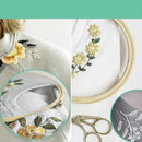 Embroidery hoop with floral design, scissors, and fabric on a light background