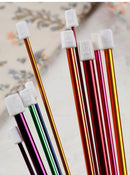 Set of colorful metal pens with white caps on a textured background