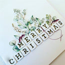 Merry Christmas message made of decorative tiles with floral elements on a white background