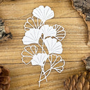 White leaf-shaped cutout on a wooden surface with pine cones.