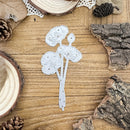 Decorative paper cutout of a floral design on a wooden surface with natural elements.