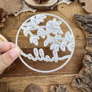 Decorative metal cutting die with floral design held over wooden surface
