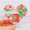 Heart-shaped card with cartoon birds and 'LOVE YOU LOTS!' text on a wooden surface