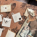 Decorative clay charms shaped like envelopes and hearts on a textured surface with floral designs.