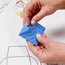 Person folding a blue paper airplane with a blurred background