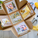 Open craft album with decorative pages and photos on a wooden surface.
