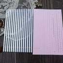 Set of metal dies and a pink paper with cut-out patterns on a wooden surface.