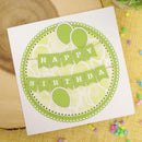 Birthday card with green balloons and 'Happy Birthday' text on a wooden surface.