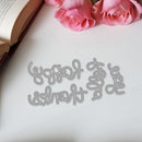 Decorative metal word cutout on a white surface with pink roses and an open book.