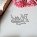 Metallic letter 'h' on a white surface with pink roses and an open book in the background.