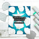 Card with seashell design and text 'Cherish our friendship, you make life fun' on a wooden surface with crafting tools.