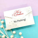 White envelope with 'Merry Christmas No Peeking!' text on a purple and blue gradient background.