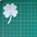 Metallic four-leaf clover on a green cutting mat with grid lines