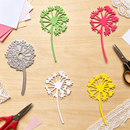 Colorful dandelion-shaped metal cutting dies on a wooden surface with scissors and paper.