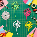 Colorful paper dandelions and scissors on a green cutting mat
