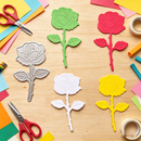 Colorful rose-shaped cutouts on a wooden surface with scissors and tape.