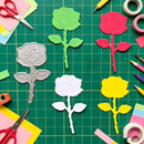 Colorful rose-shaped cutouts on a green cutting mat with craft supplies.