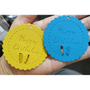 Yellow and blue round 'Happy Birthday' tags held in a hand.