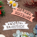 Metallic 'Happy Birthday' cutout on a textured surface with flowers and greenery.