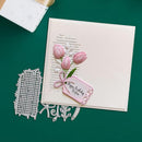 Card with pink tulips and a tag, accompanied by metal cutting dies on a green background