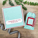 Christmas card with 'Thinking of You at Christmas' text and matching gift tag on a wooden surface.