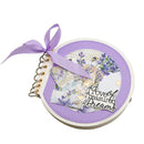 Small circular notebook with floral design and purple ribbon on a white background