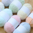 Pastel-colored yarn balls on a wooden surface