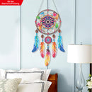 Colorful dreamcatcher hanging on a wall above a bed with a lamp and decorative pillows.