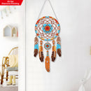 Decorative dreamcatcher with feathers hanging on a white wall.