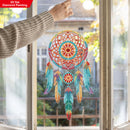 Colorful dreamcatcher hanging on a window with a blurred outdoor background