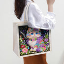 Tote bag with a colorful cat design held by a person wearing a white shirt.