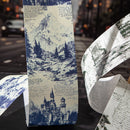 Decorative paper roll with mountain and castle design on a blurred street background