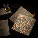 Three floral-patterned notebooks on a dark surface with a decorative object.