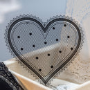Black lace heart-shaped doily on a textured surface