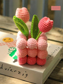 Crocheted pink tulips with green leaves on a book