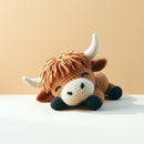 Crocheted toy bull on a white surface with a beige background