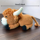 Crocheted bull toy with measurement label on a wooden surface