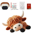 Crochet kit with a partially completed cow plush toy and various parts on a white background.