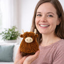 Woman holding a small brown and white stuffed animal toy, smiling at the camera.