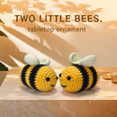 Two crochet bee ornaments on a wooden surface with 'TWO LITTLE BEES' text above.
