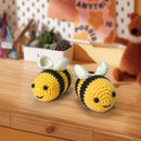 Two crochet bee toys on a wooden surface with a blurred background