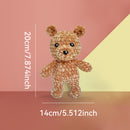 Crocheted teddy bear with measurements on a pink and yellow background