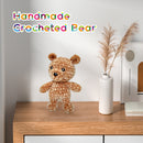 Handmade crocheted bear on a wooden surface with decorative elements.