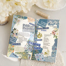 Decorative book with floral and text design on a white surface with flowers.