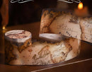 Map-themed candles with vintage world map design on a wooden surface.
